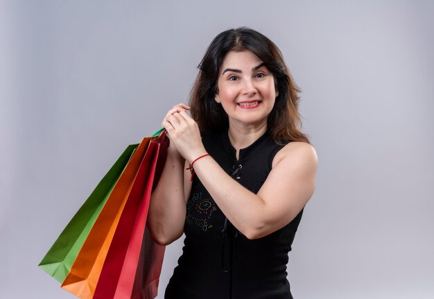 Pretty woman wearing black blouse looking happy for shopping holding bags