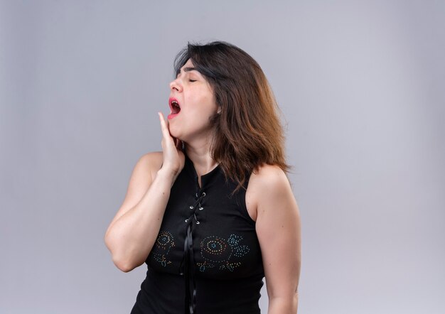 Pretty woman wearing black blouse looking sleepy yawns