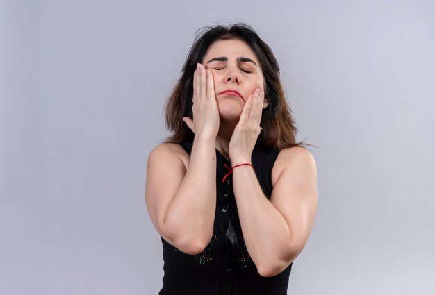 Pretty woman wearing black blouse massaging her face with hands