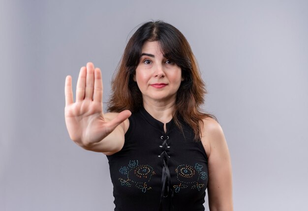 Pretty woman wearing black blouse showing stop sign with the right hand