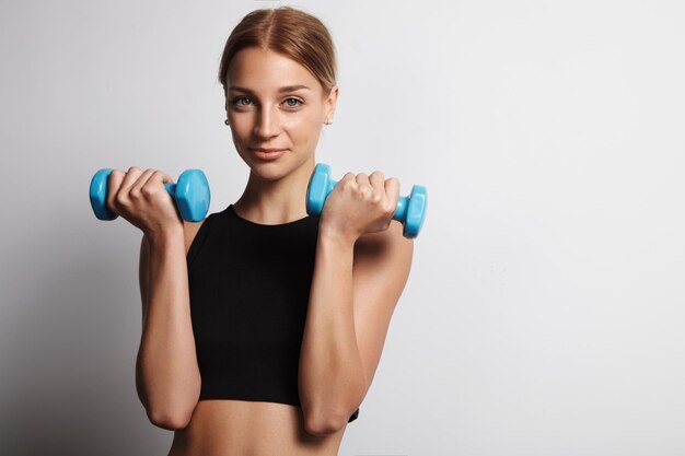 Pretty woman with a barbells in studio