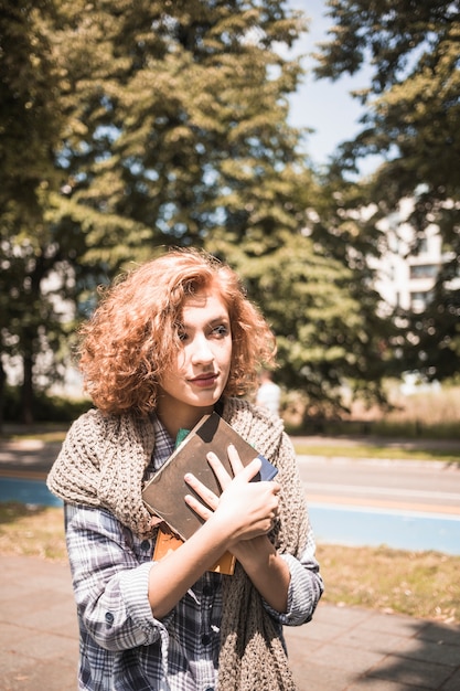 Donna graziosa con i libri in parco