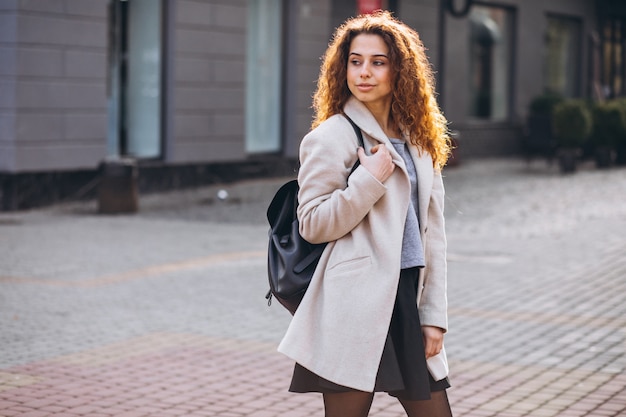 Pretty woman with curly hair walking in an autumn coat