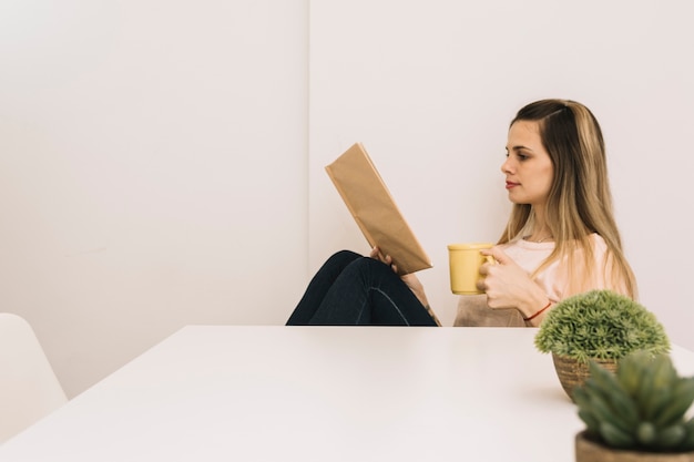 Foto gratuita donna graziosa con il libro di lettura della bevanda