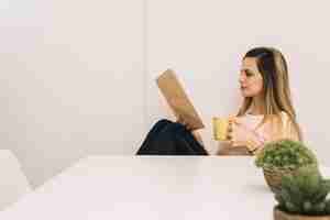 Free photo pretty woman with drink reading book