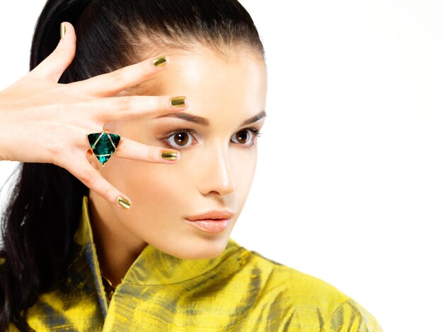 Pretty woman with golden nails and beautiful precious stone emerald - isolated on white background