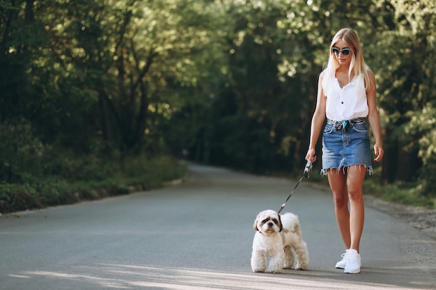 Free photo pretty woman with her dog out in the park
