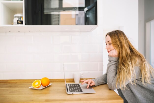 Pretty woman with laptop in kitchen