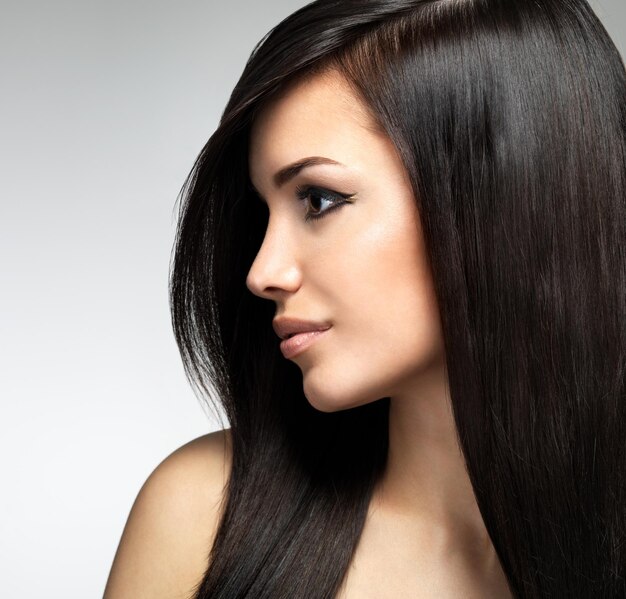 Pretty woman with long brown hairs.  Profile portrait of the fashion model posing