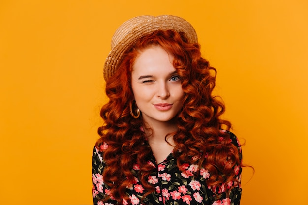 Free photo pretty woman with mole at corner of her lips winks. portrait of blue-eyed lady with wavy red hair in boater on isolated space.