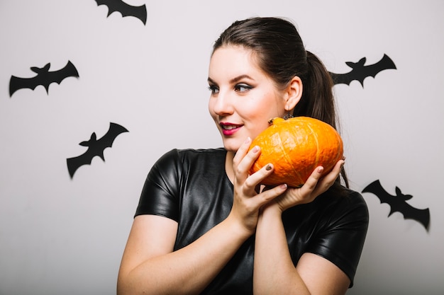 Free photo pretty woman with pumpkin in bats