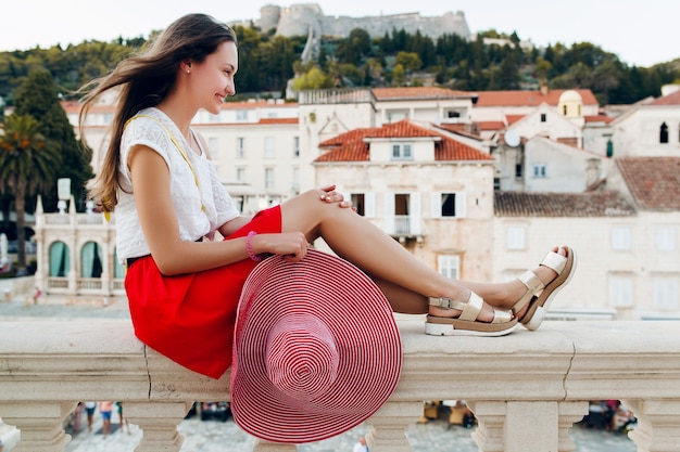 Foto gratuita bella donna con cappello rosso in vacanza gambe in sandali