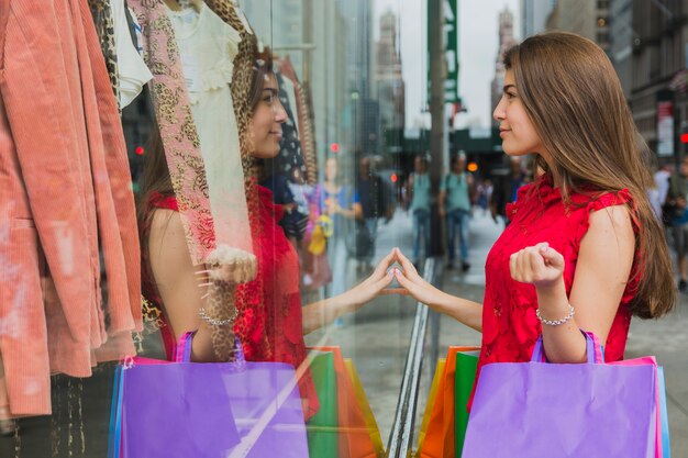 店の窓の近くのショッピングバッグを持つかわいい女性