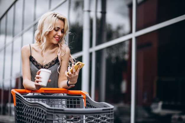 Pretty woman with shopping cart outside