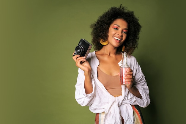 Foto gratuita bella donna con l'acconciatura stislish in posa con la macchina fotografica e bere limonata