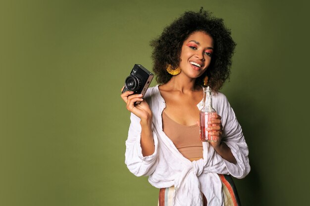 Pretty woman with stislish hairstyle posing with camera and drinking lemonade