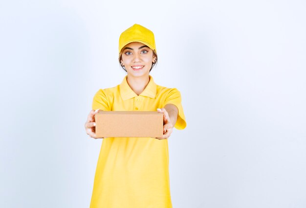 Красивая женщина в желтой форме держит коричневую пустую бумажную коробку.