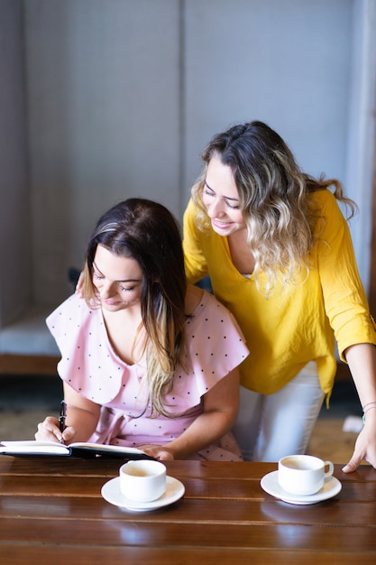 Pretty women relaxing and making notes in cafe