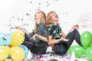 Free photo pretty women surrounded by confetti and balloons