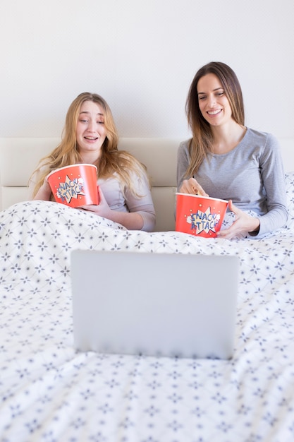 Pretty women watching film in bed