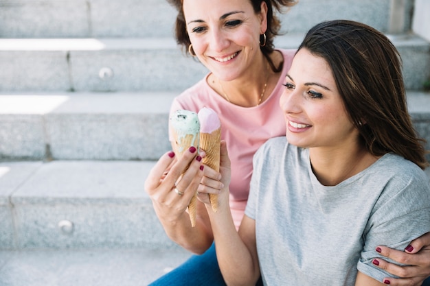 Free photo pretty women with ice-cream on stairs