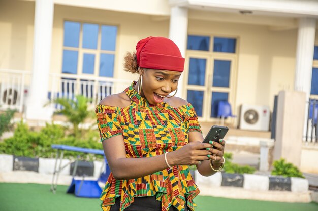 Pretty young african lady holding her phone, feeling excited