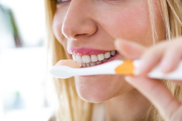 Pretty young blonde woman cleaning her teeth.