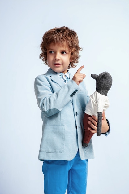 Pretty young boy in casual clothes on white studio wall