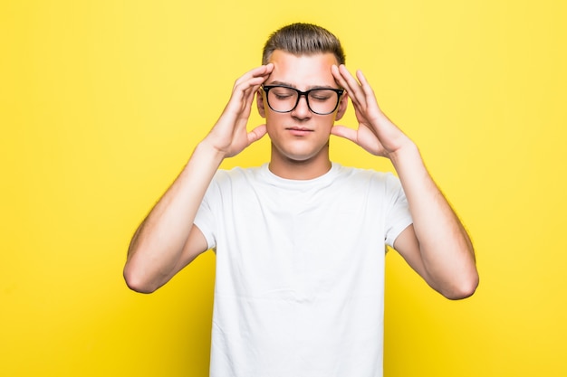 Pretty young boy shows thinking sign dressed up in white t-shirt and transperent glasses isolated on yellow