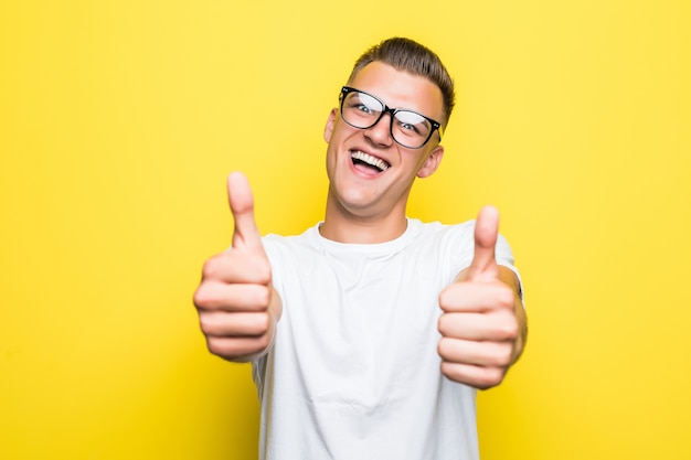 Pretty young boy shows thumbs up sign dressed up in white t-shirt and transperent glasses
