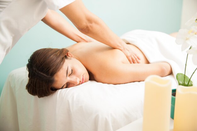 Pretty young brunette with eyes closed getting a massage and relaxing at a health clinic