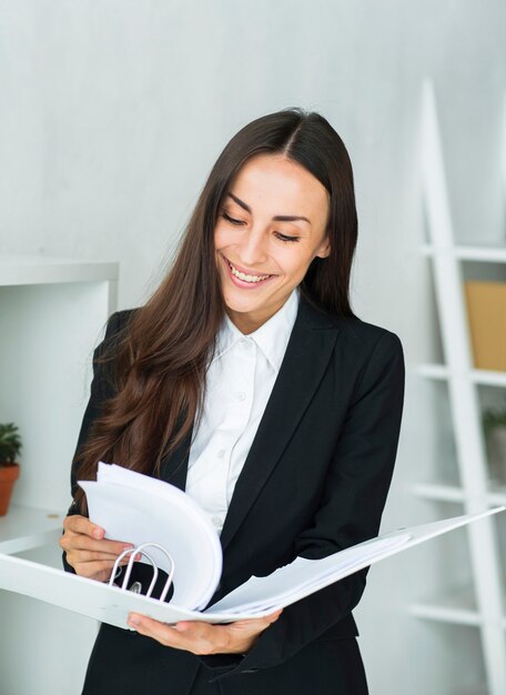 Pretty young businesswoman turning the document pages in folder