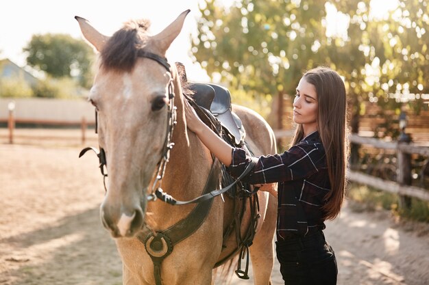 Pretty young caucasian woman in checked shirt grooming her brown