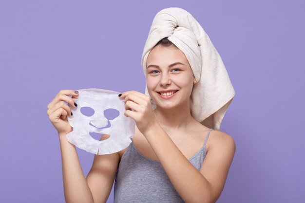 꽤 젊은 여성의 손에 뷰티 마스크를 보유하고 회춘을 위해 얼굴에 적용 할 준비가되고 있습니다.
