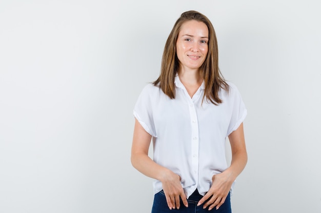 Pretty young female standing in white blouse and looking glad