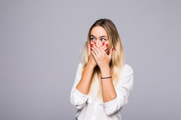 Pretty young girl covering her mouth over grey wall