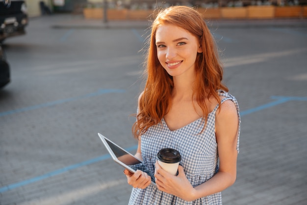 Pretty young girl holding pc tablet and cup of coffee