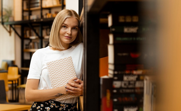 Ragazza graziosa che propone alla biblioteca