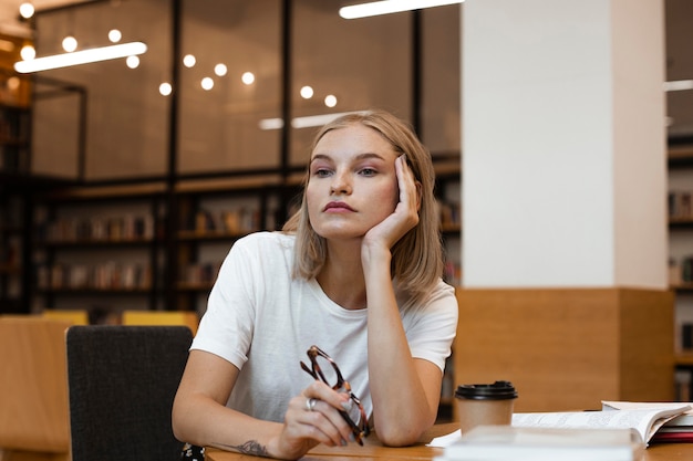 Foto gratuita ragazza graziosa che pensa alla biblioteca