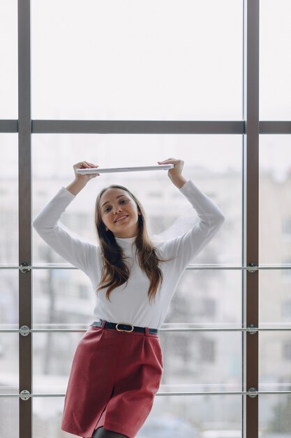 Pretty young girl with laptop by the window