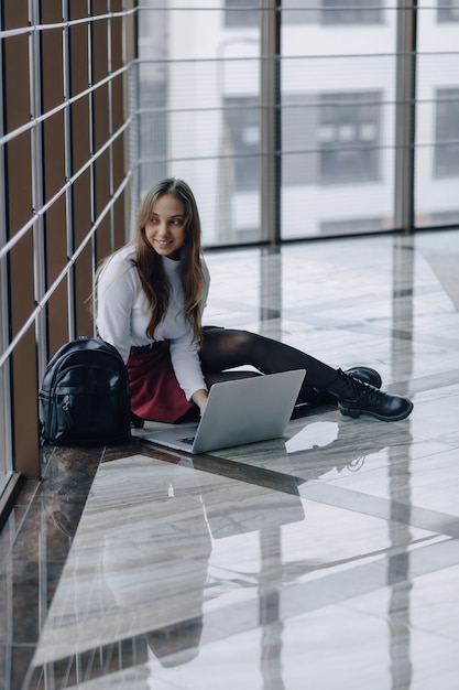 Pretty young girl with laptop by the window