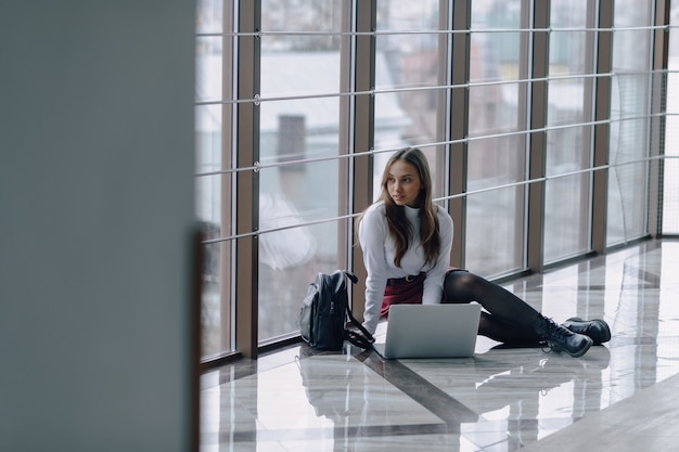 Pretty young girl with laptop by the window