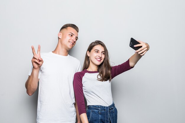 Pretty young handsome couple boy and girl making selfie on their phone isolated on white