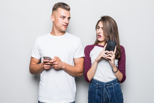 Pretty young handsome couple boy and girl with their phones isolated on white