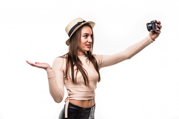 Pretty young lady in bright t-shirt and hat makes selfie on retrocamera isolated on white