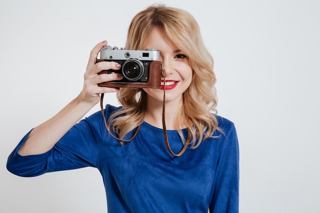 Pretty young lady holding camera over white wall