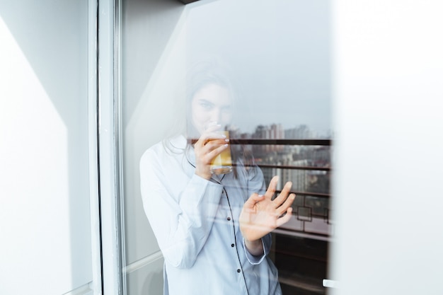 Free photo pretty young lady standing at home looking at window