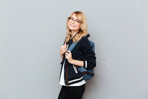 Pretty young lady student wearing glasses with backpack