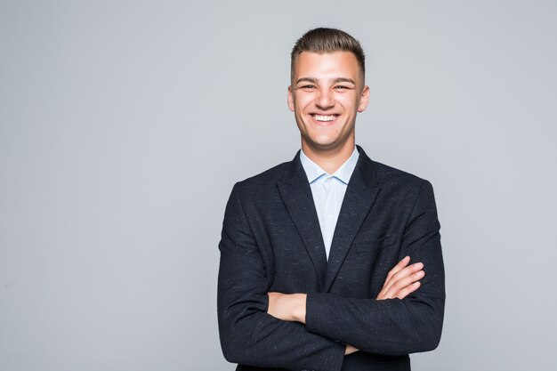 Pretty young man student businessman in jacket holds his arms crossed isolated on light grey wall