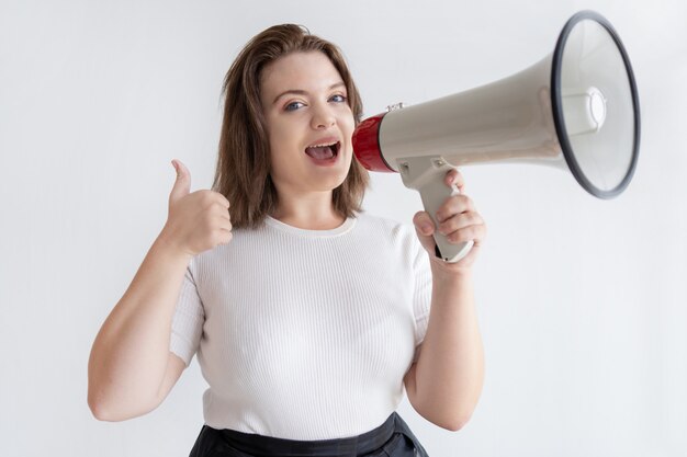 Pretty young marketing manager shouting into loudspeaker